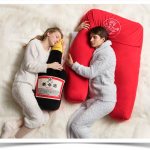 A girl and a boy sleep with pillows hugging in the shape of bottles